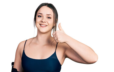 Naklejka premium Young hispanic woman wearing sportswear doing happy thumbs up gesture with hand. approving expression looking at the camera showing success.