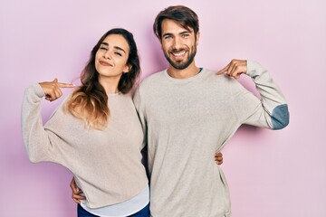 Young hispanic couple wearing casual clothes looking confident with smile on face, pointing oneself with fingers proud and happy.