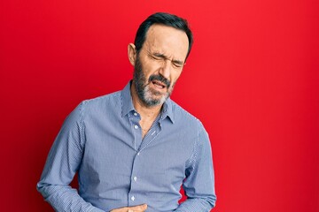 Middle age hispanic man wearing casual clothes with hand on stomach because indigestion, painful illness feeling unwell. ache concept.