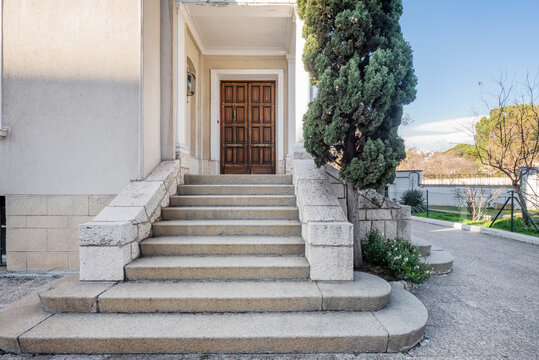 Granite stone stairs that give access to a wooden door with an entrance panel to a private home
