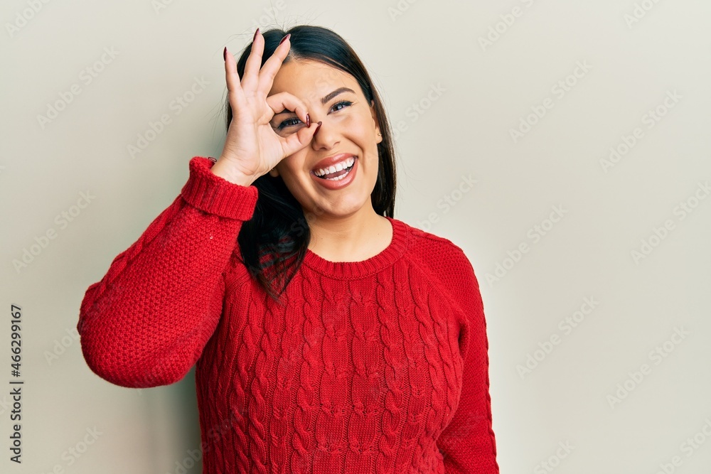 Sticker beautiful brunette woman wearing wool winter sweater doing ok gesture with hand smiling, eye looking