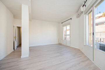 Newly painted empty room with wooden floors, floor-to-ceiling viewpoints and air conditioning unit