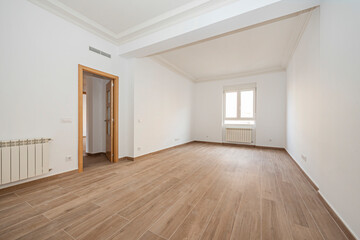 Fototapeta premium Empty room with radiator, oak-colored woodwork, wooden floors and window in the background
