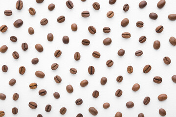 Fresh dark brown coffee beans on white table. Pattern background. Closeup. Top down view.