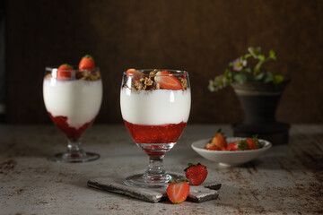 Bowl of granola with yogurt, milk and fresh raspberries, blueberries, mango for a healthy breakfast on the dark background