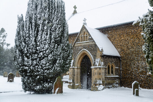 All Saints church in the small village of Sutton in the British countryside, it is totally covered in deep snow during a rare snow storm in the UK