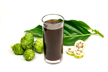 Noni juice in transparent glass and fresh noni fruit with green leaf isolated on white background.