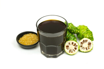 Noni juice in transparent glass cup and fresh noni fruit isolated on white background.