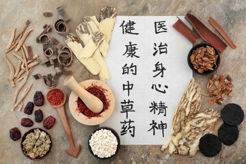 Ancient Chinese herbal medicine with herbs, spice and calligraphy script on rice paper. Translation reads as traditional Chinese herbs to heal mind body and spirit. Natural health care concept.