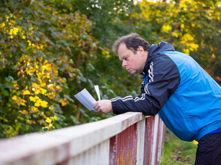 Man reading letter and leaning on the railing, worried and sad