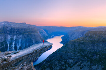 Alone tourist on Trolltunga rock - most spectacular and famous scenic cliff in Norway