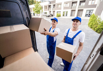 Two removal company workers unloading boxes from minibus