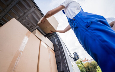 Two removal company workers unloading boxes from minibus