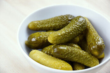 Pickled cucumbers in a bowl stock images. Marinated gherkins in a white bowl on the table stock photo