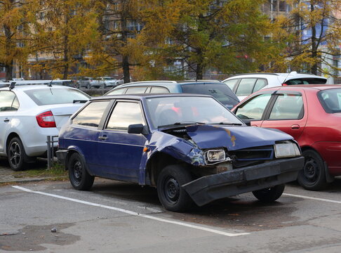 A broken blue passenger car is parked in a street parking lot, Dybenko Street, St. Petersburg, Russia, October 2021