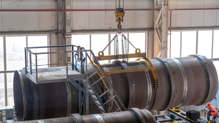 Moving pipes inside the workshop with an overhead crane using a traverse.
