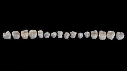 Perfectly laid out dental crowns with morphology on black glass, top view