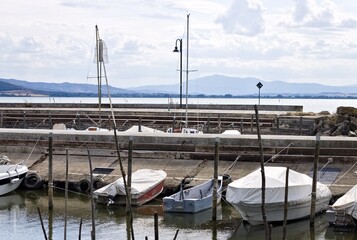 Small motor boats moored on wooden poles of the pier of a small port in Lake Trasimeno (Umbria, Italy, Europe) - 466309770
