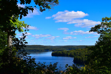 Lake with cloudy sky, surrounded by lush green foliage, in Algonquin Park, Canada