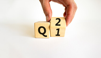 From 1st to 2nd quarter symbol. Businessman turns a wooden cube and changes words 'Q1' to 'Q2'. Beautiful white table, white background. Business, happy 2nd quarter Q2 concept, copy space.
