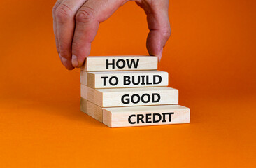 Symbol of building success foundation and good credit symbol. Wooden blocks with words how to build good credit. Beautiful orange background. Businessman hand. Business and build good credit concept.