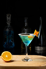curaçao blue cacktail , blue margarita one on a wooden board blurred drink bottles on a dark background