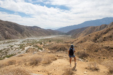 Fototapeta na wymiar A Woman Hiker Exploring and Overlooking the California Desert Whitewater River Valley from the Trail Above