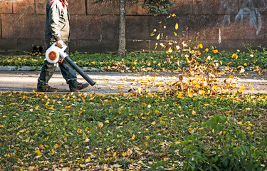 Cleaning dry leaves with a windmill. A municipal worker cleans up the city park.