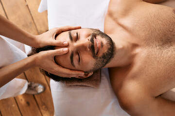 Relaxing anti-stress head massage. Handsome man relaxes in a massage parlor during head massage,...