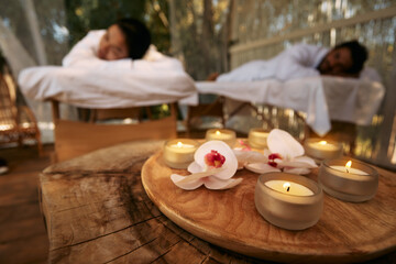 Aroma massage for couple at spa resort. Couple lying on massage tables during day-spa and romantic weekend with candles and orchid flowers