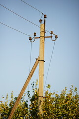 Electric pole with wires near tree in blue clear sky