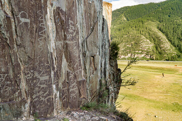 Rock carvings of ancient people in Kalbak-Tash, in the distance there is the Chuisky Deer stone Adyr-Kan or Olenny stone