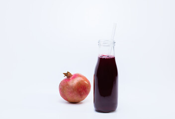 Ripe pomegranate with bottle of pomegranate juice on white background