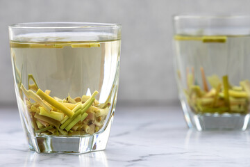 Tea beverage of dry cut lemon grass herb in glass cup.