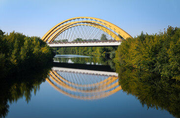 The arched bridge on the western Berliner Ring over the Havel Canal near Brieselang. It is a sunny day. The bridge is reflected in the water.