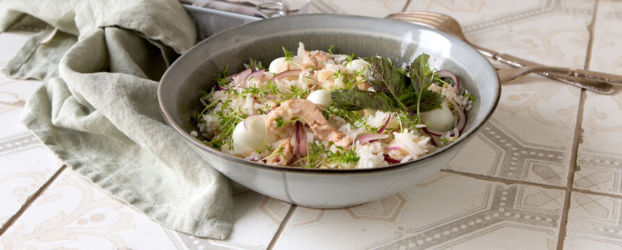 bowl of salad with cod liver, rice and eggs on a light table