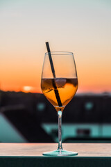 Glass with orange cocktail Aperol Spritz on a balcony in the sunset, vertical