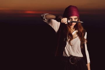 Outdoor portrait of young female in pirate costume with a knife