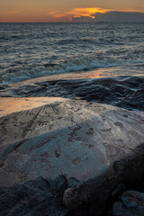 Old petroglyphs on Cape Besov nose in Lake Onega in Karelia in northern Russia at summer  sunset
