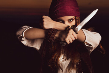 Outdoor portrait of young female in pirate costume with a knife