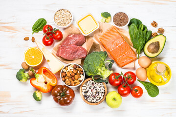 Healthy food products. Balanced nutrition. Salmon fish, beef, beans, nuts and vegetables with olive oil. Top view image at white table. - obrazy, fototapety, plakaty