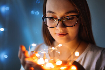 woman in glasses holding christmas lights