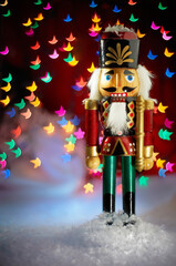 Christmas nutcracker standing in front of decorated Christmas tree. Christmas lights bokeh at background.