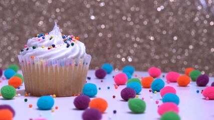 Decorated colourful cupcake for the holiday, shallow depth of field. Close up macro focus on the iced muffin. Gold background. Presentation of delicious desserts at anniversary or birthday.