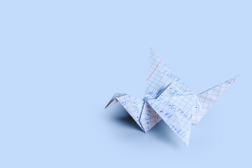The paper crane is made of a squared notebook sheet. Traditional origami from paper. Horizontal...