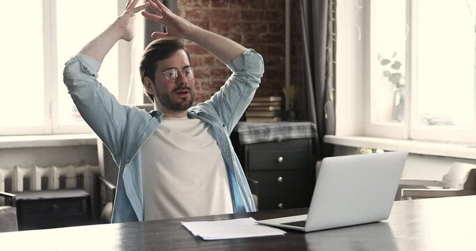 Young satisfied businessman office employee finish work on laptop leaned on chair with hands behind head smile enjoy break and successful project accomplishment. Modern office, climate control concept