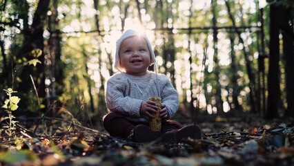 child playing in the autumn forest, little baby eating corn, healthy life