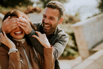 Young man covering the eyes of his girlfiend in the park