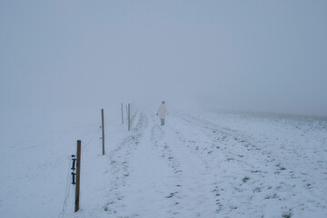 Lonely Woman walking alone in snow landscape