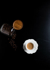 Little porcelain cap of coffee and  a jar full of coffee beans  